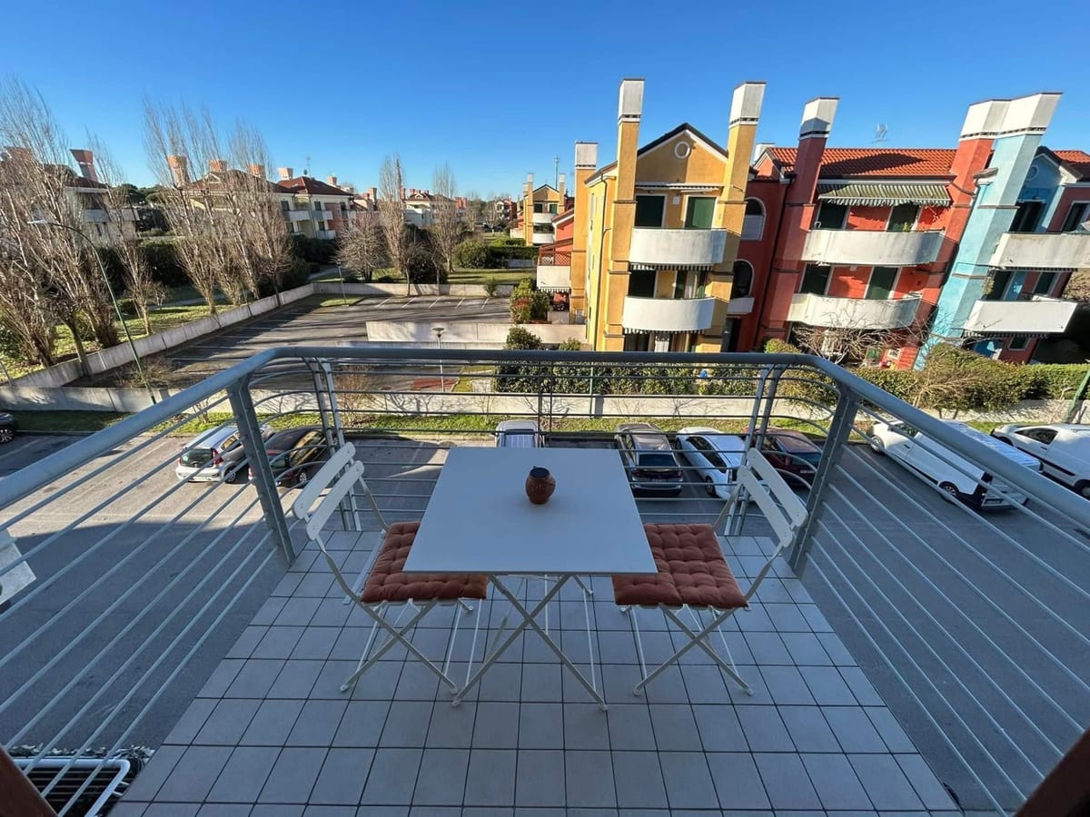 Balcone con tavolino e due sedie, affacciato sulle case colorate del residence