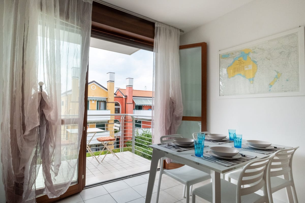 Tavolo da pranzo per quattro accanto alla portafinestra aperta sul balcone
