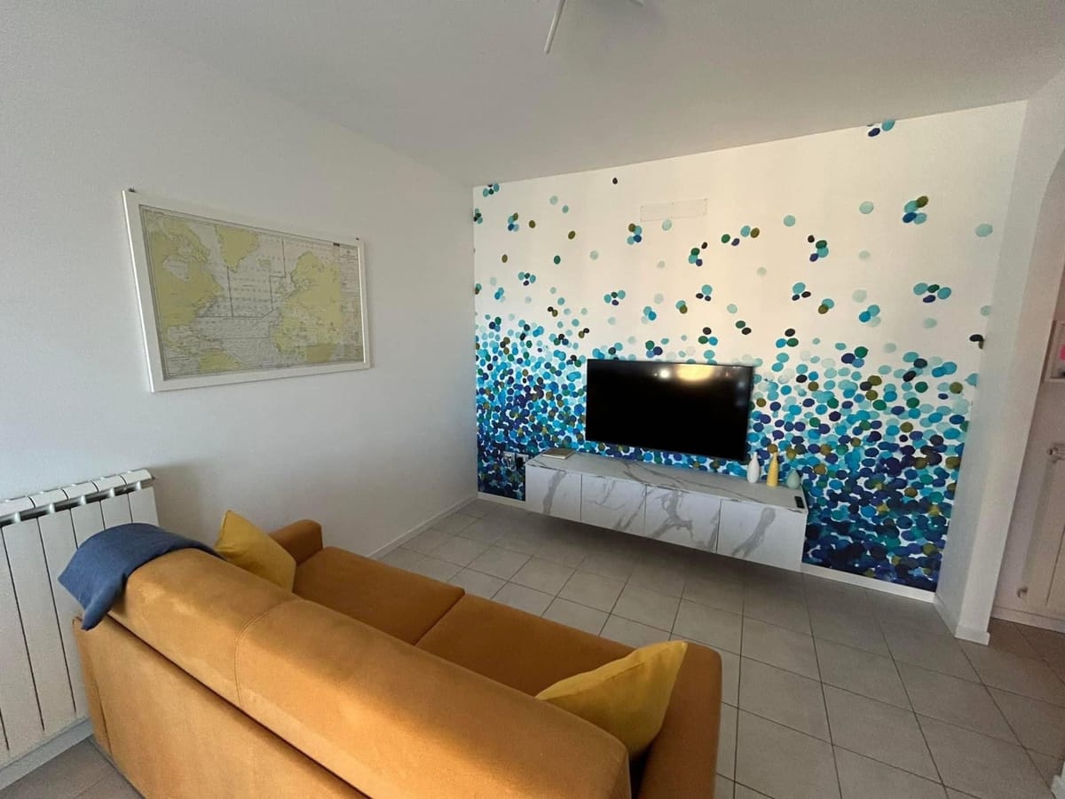 Parete dipinta a mano con pois blu e turchesi dietro la TV, mobile effetto marmo