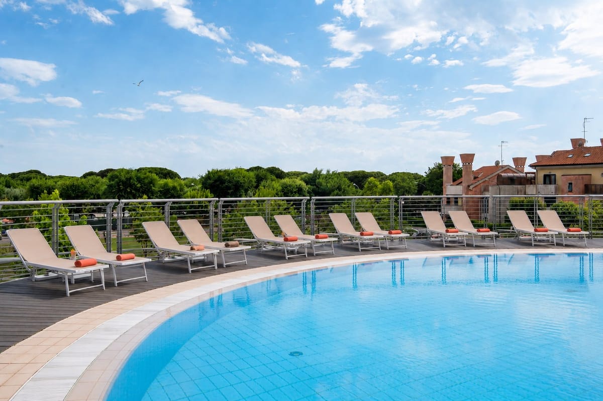 Piscina del residence vista dal bordo, con lettini e palazzine del complesso